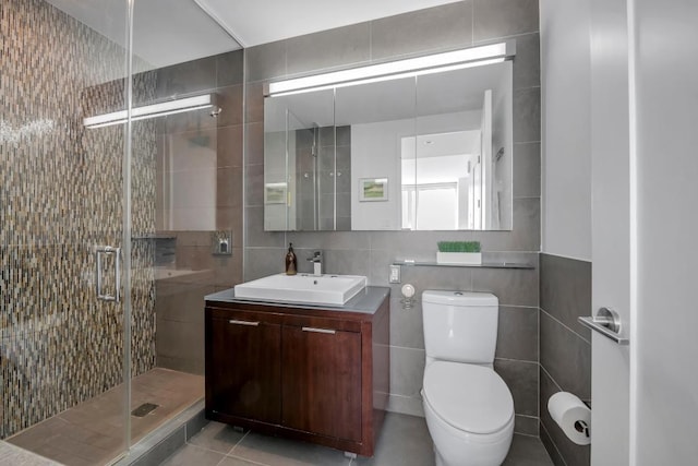 bathroom with toilet, vanity, a shower stall, and tile walls