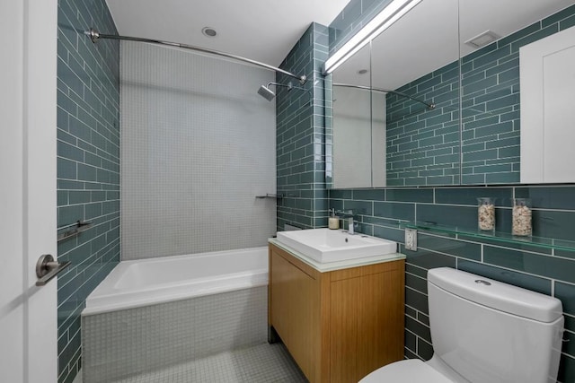 bathroom with tiled shower / bath, tile walls, toilet, and vanity