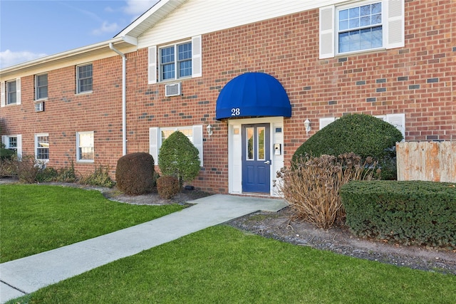 doorway to property featuring a lawn and brick siding