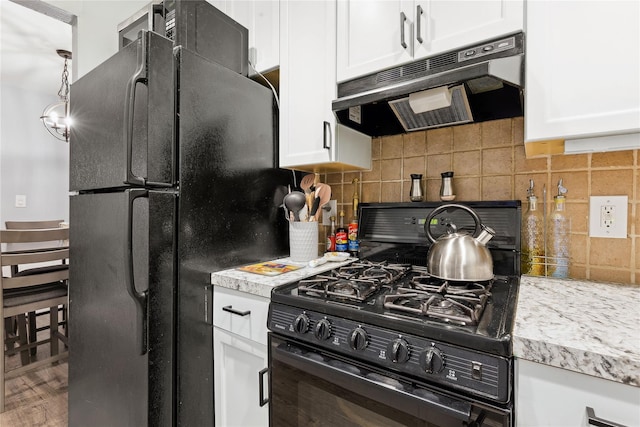 kitchen with under cabinet range hood, white cabinets, light countertops, backsplash, and black appliances