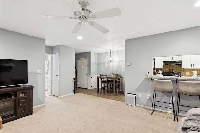 living area with a ceiling fan, recessed lighting, light colored carpet, and baseboards