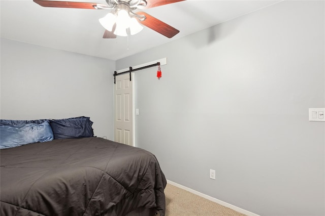 bedroom with carpet floors, a barn door, baseboards, and ceiling fan