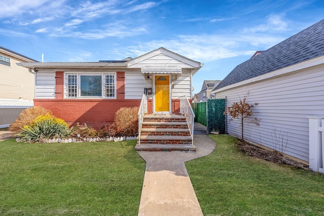 view of front of house with brick siding, fence, and a front lawn