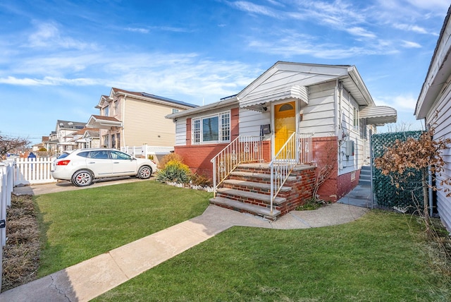 bungalow-style home with brick siding, a front lawn, and fence