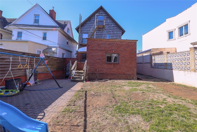 rear view of property with brick siding and fence