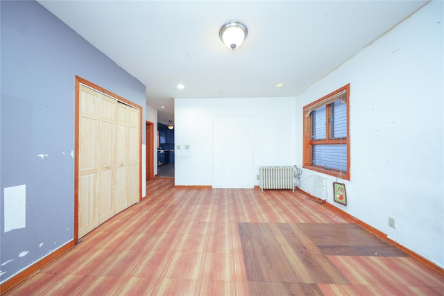 spare room featuring radiator and light wood finished floors