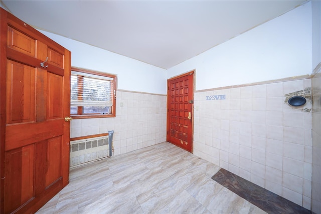 spare room with radiator, tile walls, and wainscoting