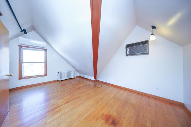 bonus room featuring a wall mounted air conditioner, an AC wall unit, wood finished floors, radiator heating unit, and vaulted ceiling