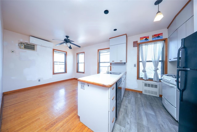 kitchen featuring black appliances, white cabinets, light wood finished floors, and a sink