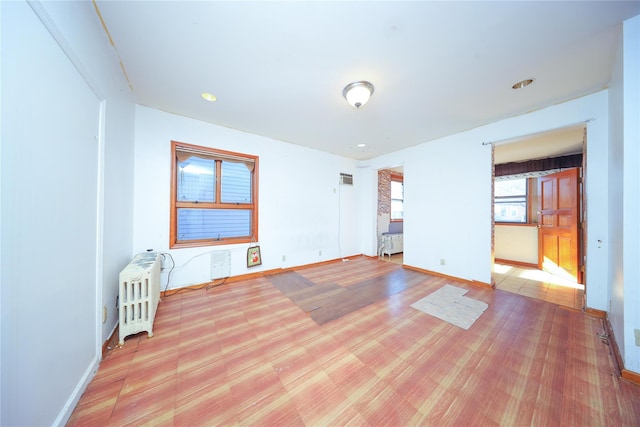 unfurnished room featuring radiator and baseboards