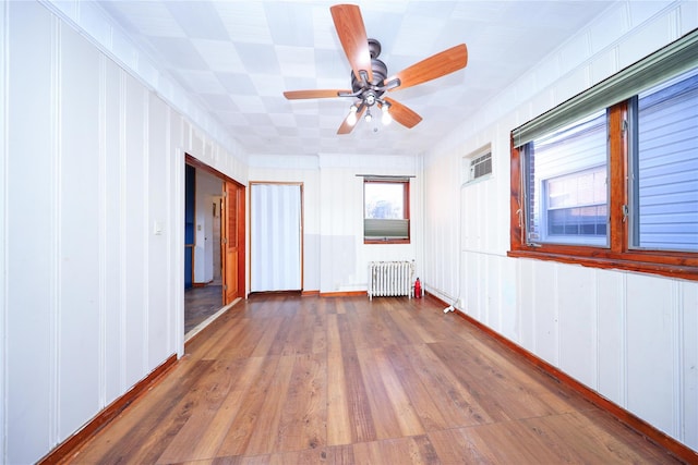 unfurnished room featuring radiator, wood finished floors, and ceiling fan