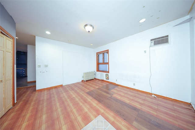 empty room with baseboards, radiator heating unit, light wood-style flooring, recessed lighting, and a wall mounted AC