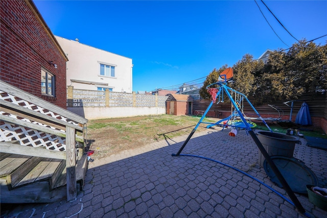 view of patio / terrace featuring an outbuilding, a shed, a playground, and fence