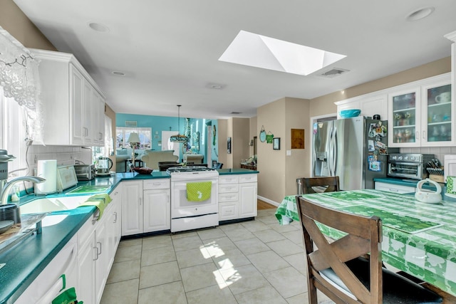 kitchen with white gas range oven, stainless steel fridge with ice dispenser, a peninsula, white cabinetry, and a sink