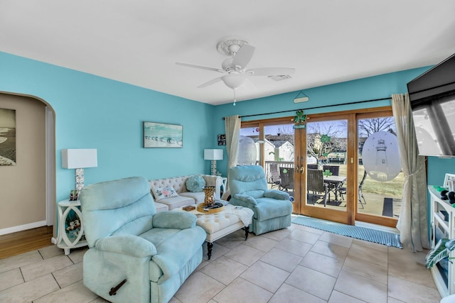 tiled living area with arched walkways, french doors, visible vents, a ceiling fan, and baseboards