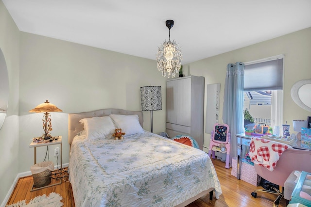 bedroom with light wood-type flooring, an inviting chandelier, and baseboards