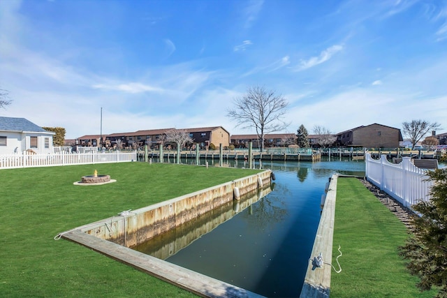 view of dock featuring a water view, fence, and a lawn