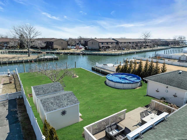 view of dock with a water view, a yard, and fence