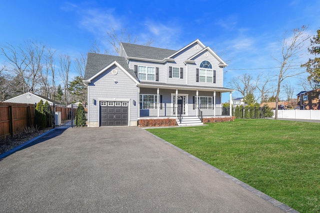 view of front facade with fence, covered porch, a shingled roof, a front lawn, and aphalt driveway