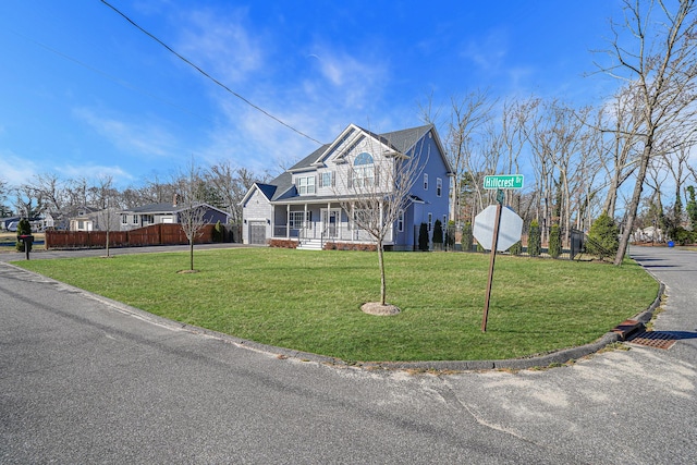 view of front of house with driveway, a porch, a front lawn, and fence