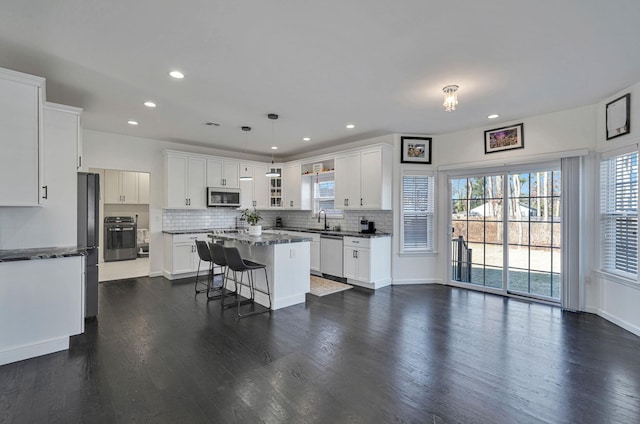 kitchen featuring a wealth of natural light, stainless steel appliances, tasteful backsplash, and a center island