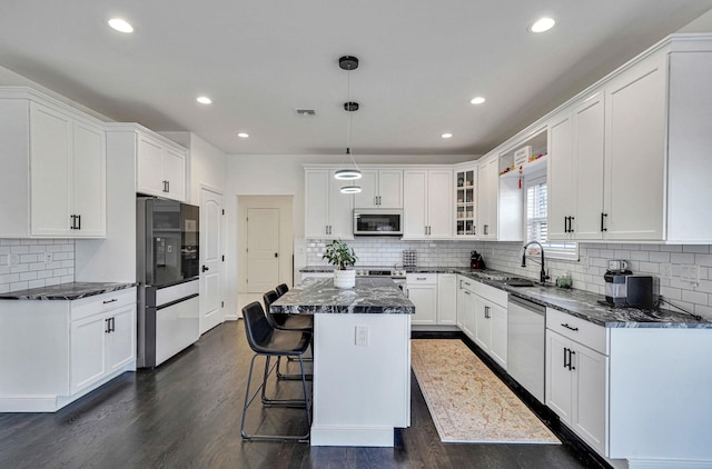 kitchen with a sink, dark wood-type flooring, a kitchen island, and stainless steel appliances