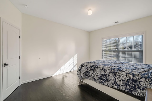 bedroom featuring wood finished floors, visible vents, and baseboards