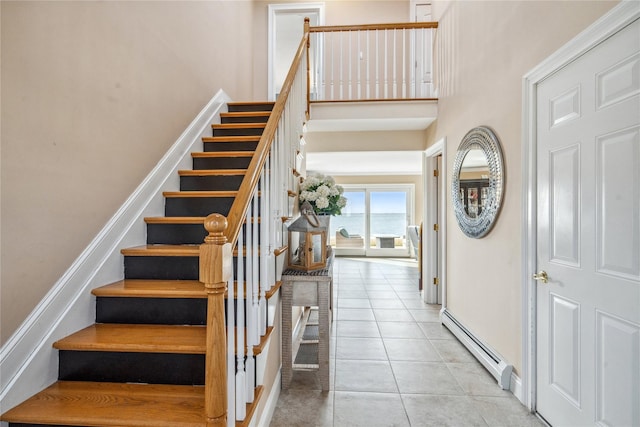 stairs with tile patterned floors, baseboards, a towering ceiling, and a baseboard radiator