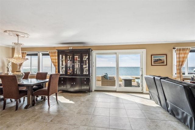 dining room with light tile patterned floors, a water view, an inviting chandelier, and ornamental molding