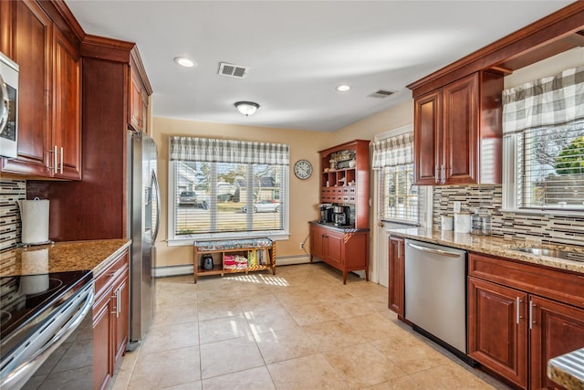 kitchen with visible vents, stainless steel appliances, light tile patterned flooring, light stone countertops, and baseboard heating