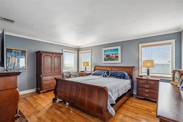 bedroom with light wood-style flooring, baseboards, visible vents, and ornamental molding