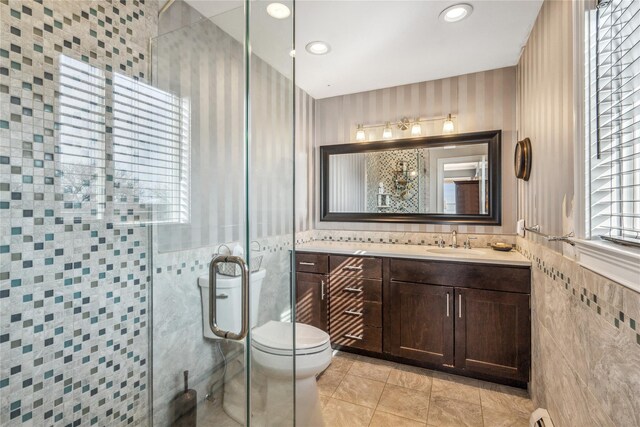 full bathroom featuring tile patterned flooring, toilet, vanity, a stall shower, and tile walls