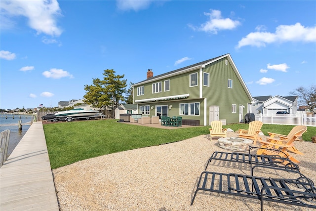 rear view of property featuring fence, a yard, a fire pit, a chimney, and a patio area