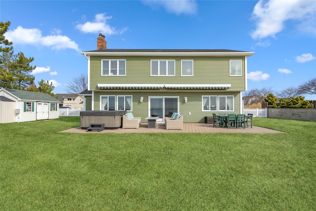 back of property with a patio, fence, a chimney, a hot tub, and a lawn