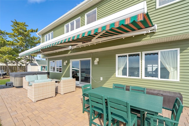 view of patio / terrace featuring outdoor dining space, fence, and a hot tub