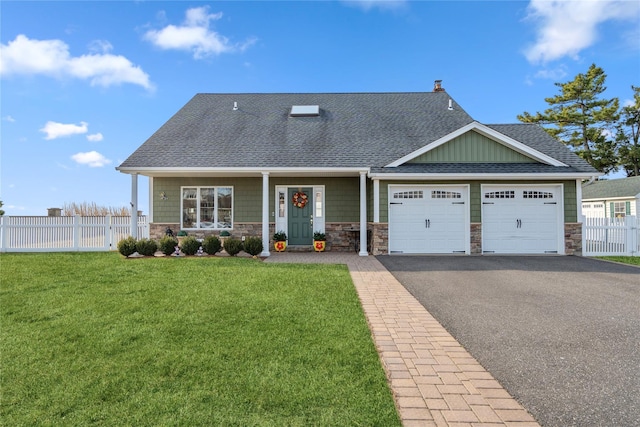 craftsman-style house featuring fence, a shingled roof, a front lawn, a garage, and aphalt driveway