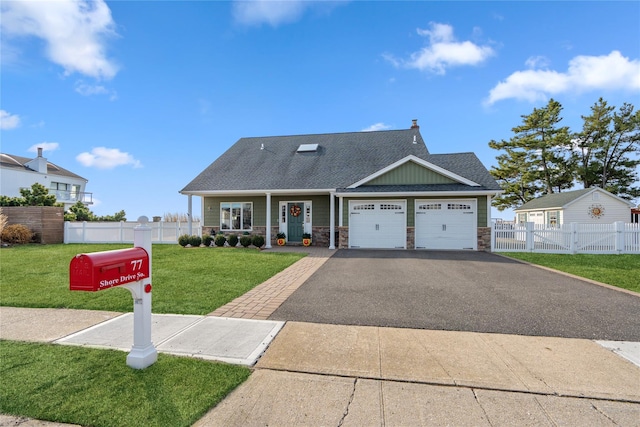 view of front of house with stone siding, driveway, a front yard, and fence