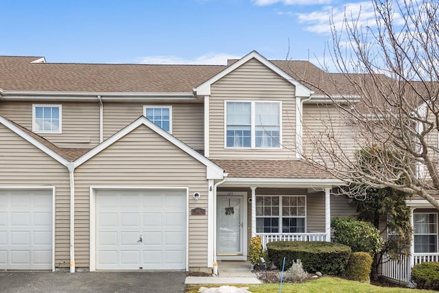 multi unit property featuring driveway, a garage, a porch, and roof with shingles