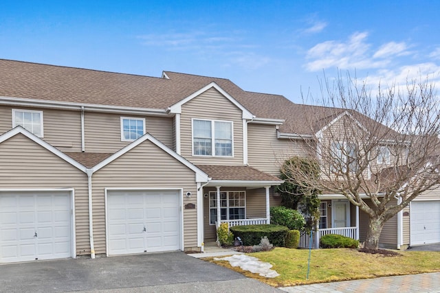 view of property featuring roof with shingles, a porch, an attached garage, a front yard, and driveway