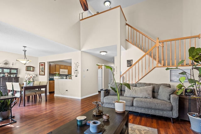 living room featuring a high ceiling, stairway, wood finished floors, and baseboards