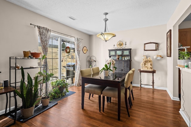 dining area featuring visible vents, a textured ceiling, baseboards, and wood finished floors