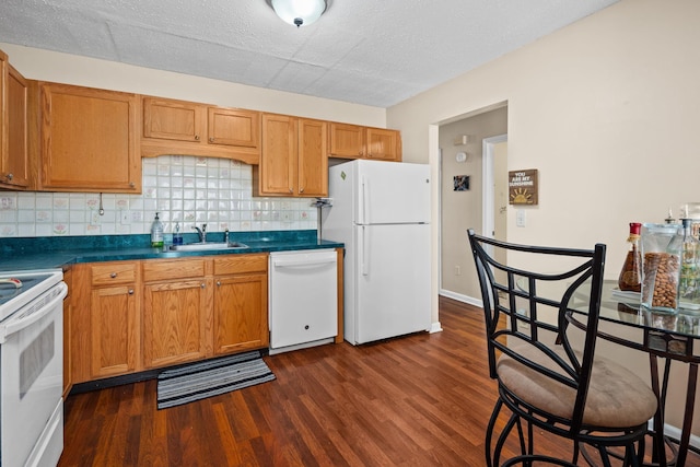 kitchen with white appliances, backsplash, dark wood-style flooring, and a sink