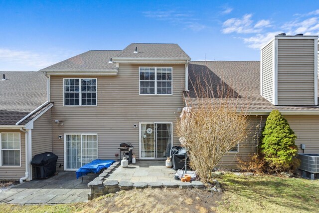 back of house with roof with shingles, cooling unit, and a patio