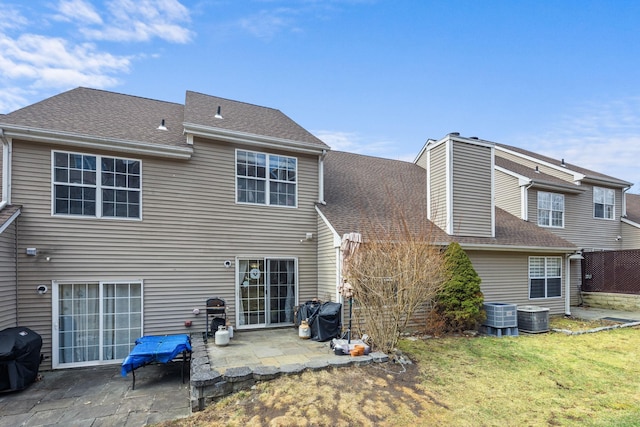 rear view of property with a patio, a yard, a shingled roof, and central air condition unit