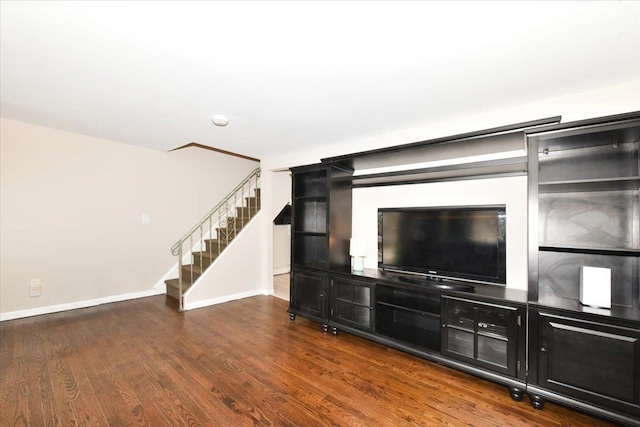 unfurnished living room with stairs, baseboards, and wood finished floors