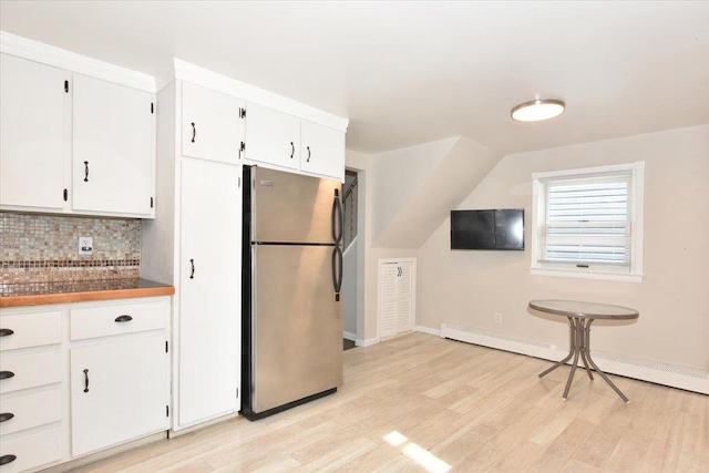 kitchen with tasteful backsplash, a baseboard radiator, light wood-style floors, freestanding refrigerator, and white cabinets