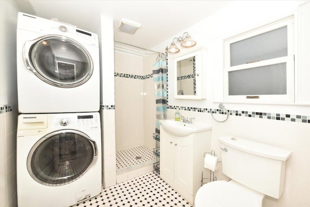 clothes washing area with stacked washer / dryer, laundry area, a sink, and tile walls