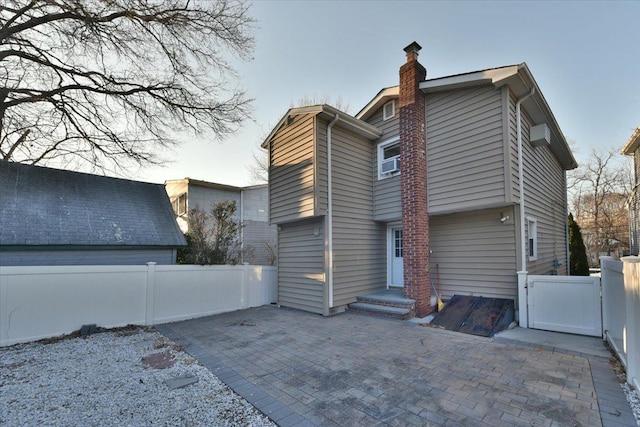 exterior space featuring a gate, a patio area, fence, and a chimney