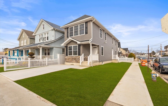 view of front facade featuring a front yard, stone siding, and fence