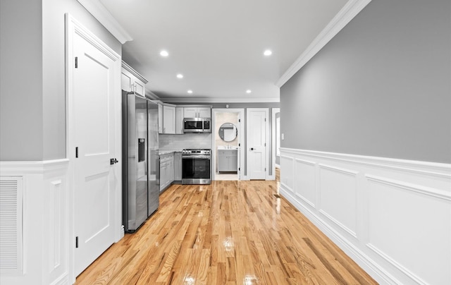 kitchen with recessed lighting, light countertops, ornamental molding, appliances with stainless steel finishes, and backsplash